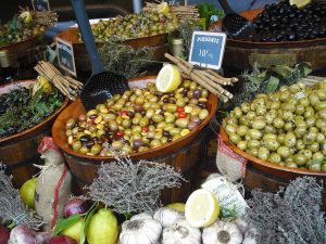 Seau d’olives exposé sur un étal de marché provençal avec produits du terroir